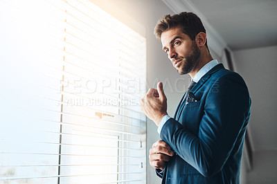 Buy stock photo Cropped shot of a handsome young man fastening his cuffs in his bedroom at home