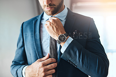 Buy stock photo Cropped shot of an unrecognizable young man putting on a tie in his bedroom at home