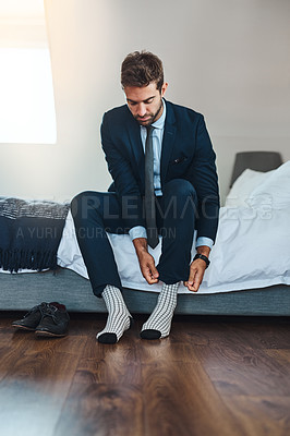 Buy stock photo Full length shot of a handsome young man putting his socks on in his bedroom at home