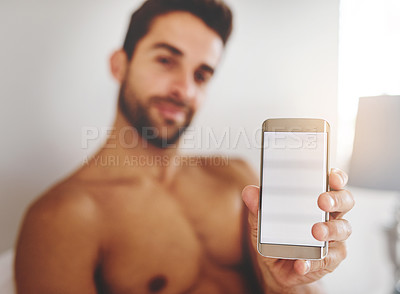 Buy stock photo Cropped portrait of a handsome young man holding up a cellphone in his bedroom at home