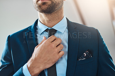 Buy stock photo Cropped shot of an unrecognizable young man putting on a tie in his bedroom at home