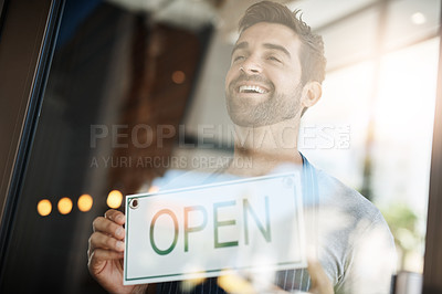 Buy stock photo Happy man, cafe and window with open sign for welcome, entrance or small business at indoor restaurant. Young male person or owner with smile, billboard or poster ready for service at coffee shop