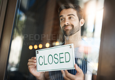 Buy stock photo Shot of a handsome young man hanging up a closed sign on the door of his store