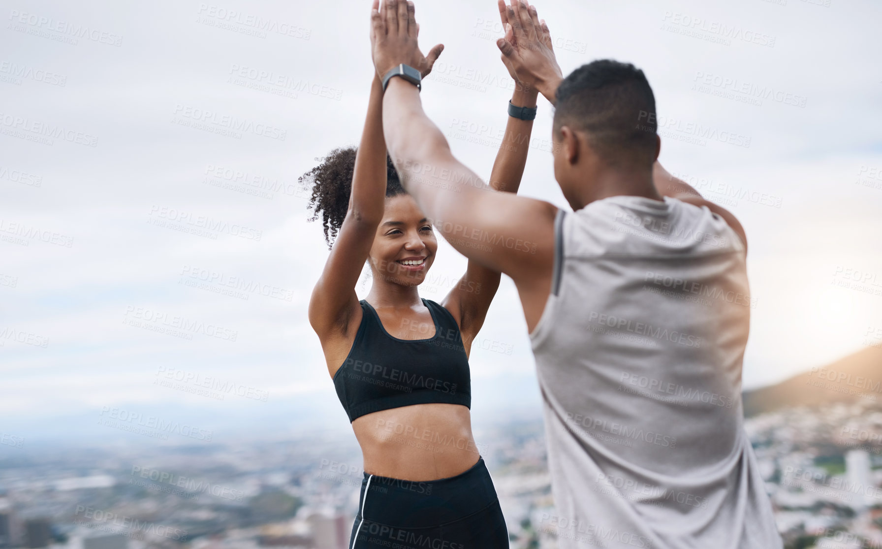 Buy stock photo Shot of a sporty young couple high fiving each other while exercising outdoors