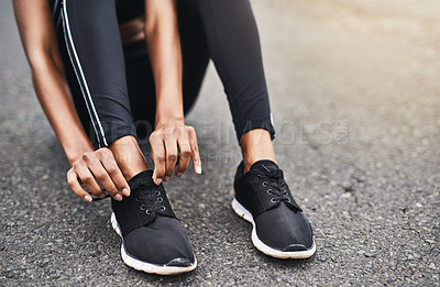 Buy stock photo Closeup shot of a sporty woman tying her shoelaces while exercising outdoors