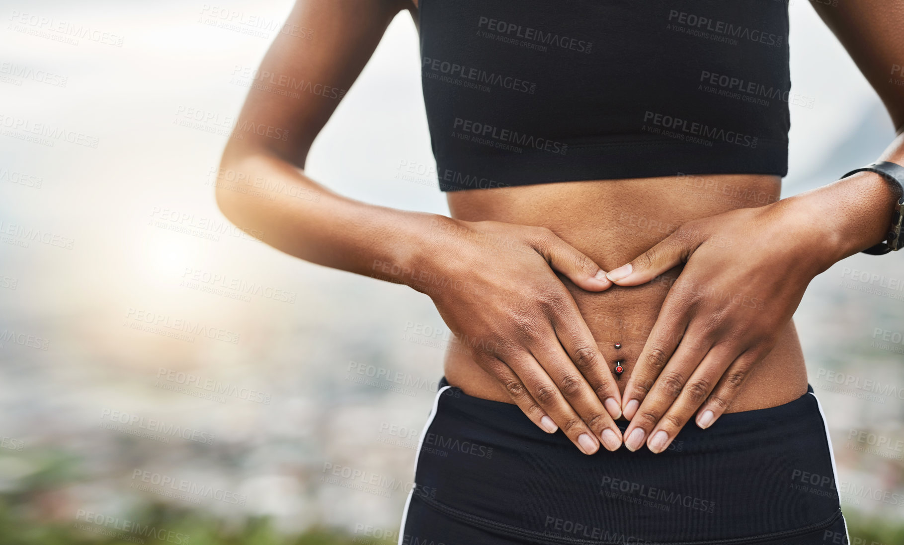 Buy stock photo Closeup shot of a sporty unrecognizable woman making a heart shape with her hands on her stomach outside
