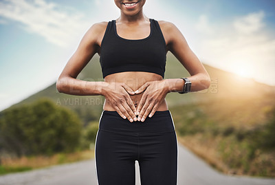 Buy stock photo Closeup shot of a sporty unrecognizable woman making a heart shape with her hands on her stomach outside