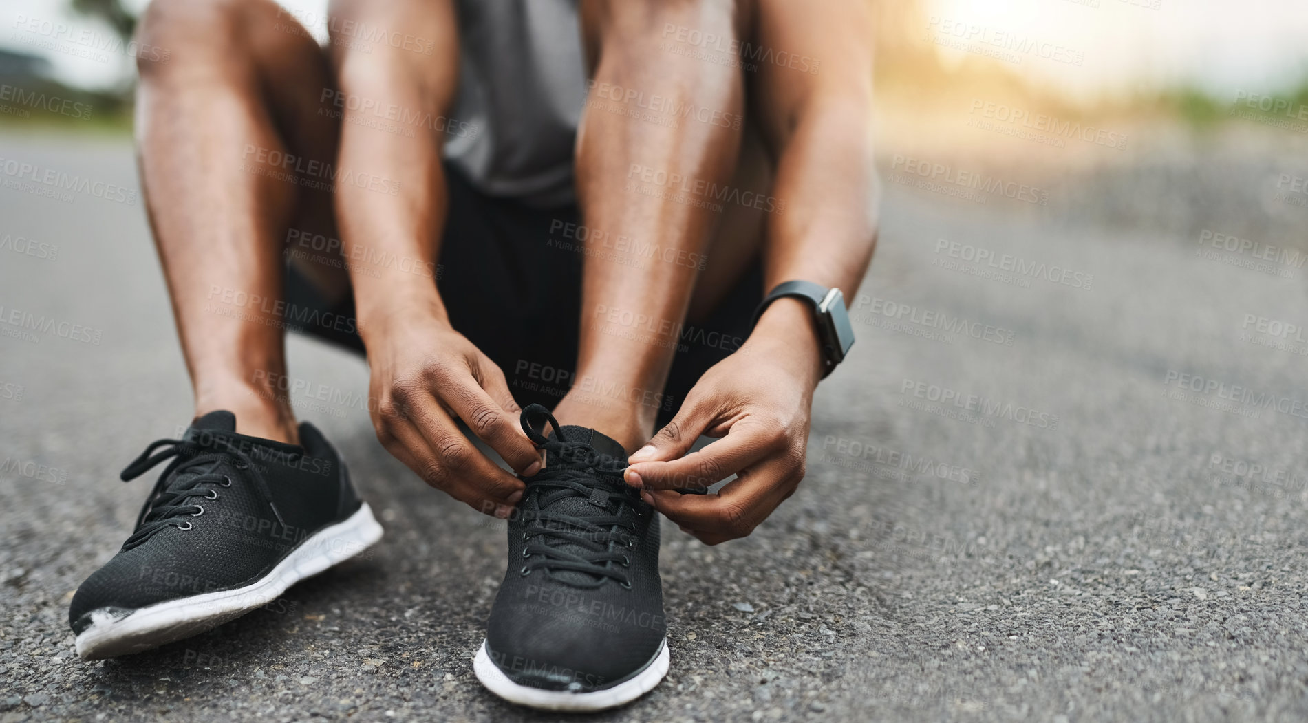 Buy stock photo Closeup shot of a sporty man tying his shoelaces while exercising outdoors