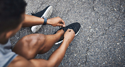 Buy stock photo High angle shot of a sporty man tying his shoelaces while exercising outdoors