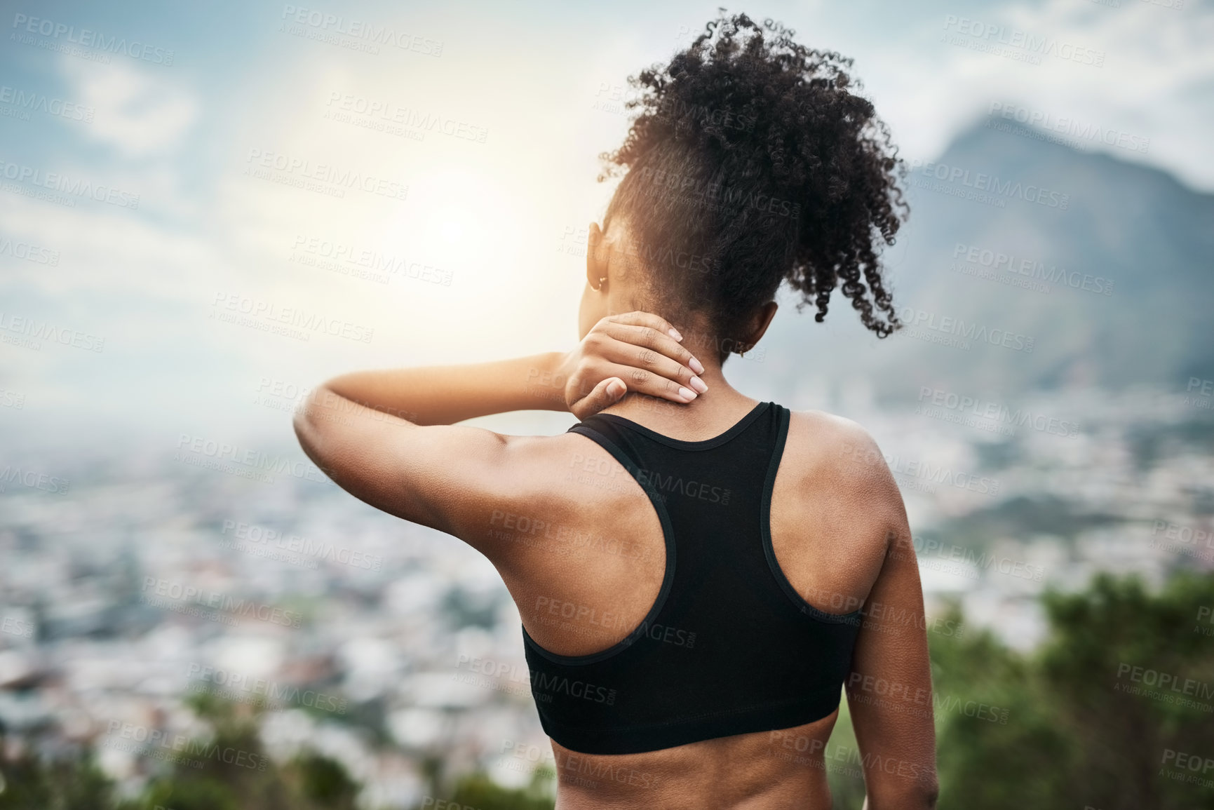 Buy stock photo Rearview shot of a sporty young woman holding her neck while exercising outdoors