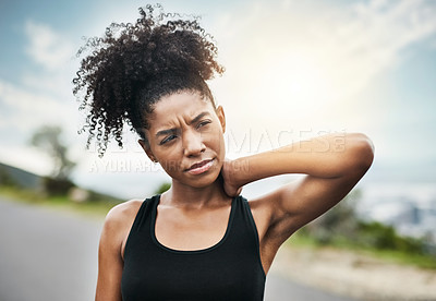 Buy stock photo Shot of a sporty young woman holding her neck in pain while exercising outdoors