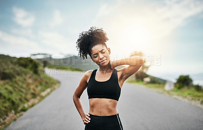 Buy stock photo Shot of a sporty young woman holding her neck in pain while exercising outdoors
