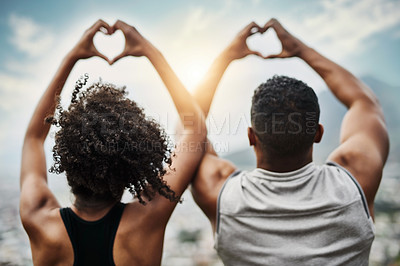 Buy stock photo Rearview shot of a sporty young couple making heart shapes with their hands while exercising outdoors
