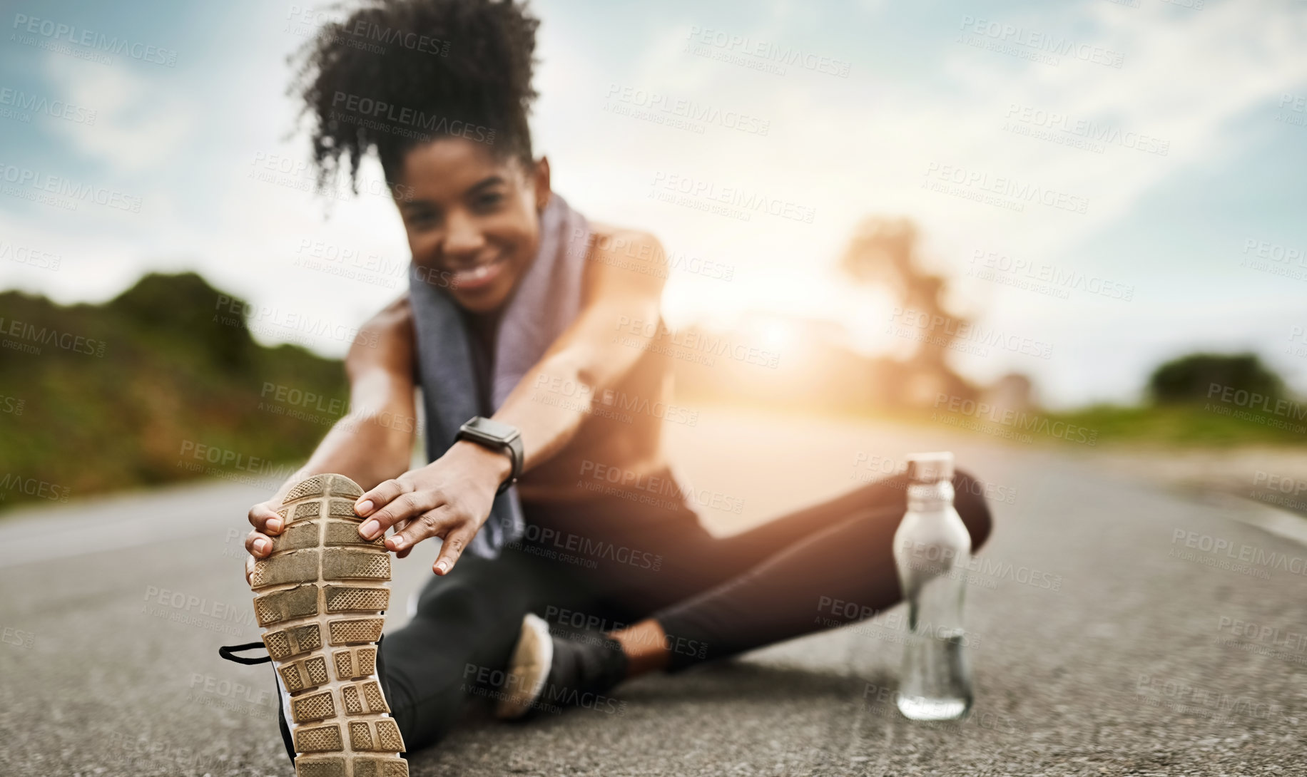 Buy stock photo Portrait of a sporty young woman stretching her legs while exercising outdoors