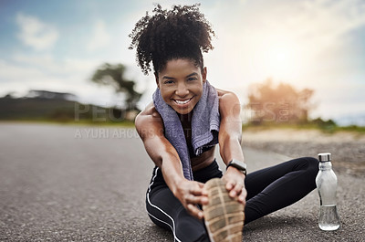 Buy stock photo Portrait of a sporty young woman stretching her legs while exercising outdoors