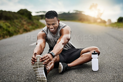 Buy stock photo Shot of a sporty young man stretching his legs while exercising outdoors