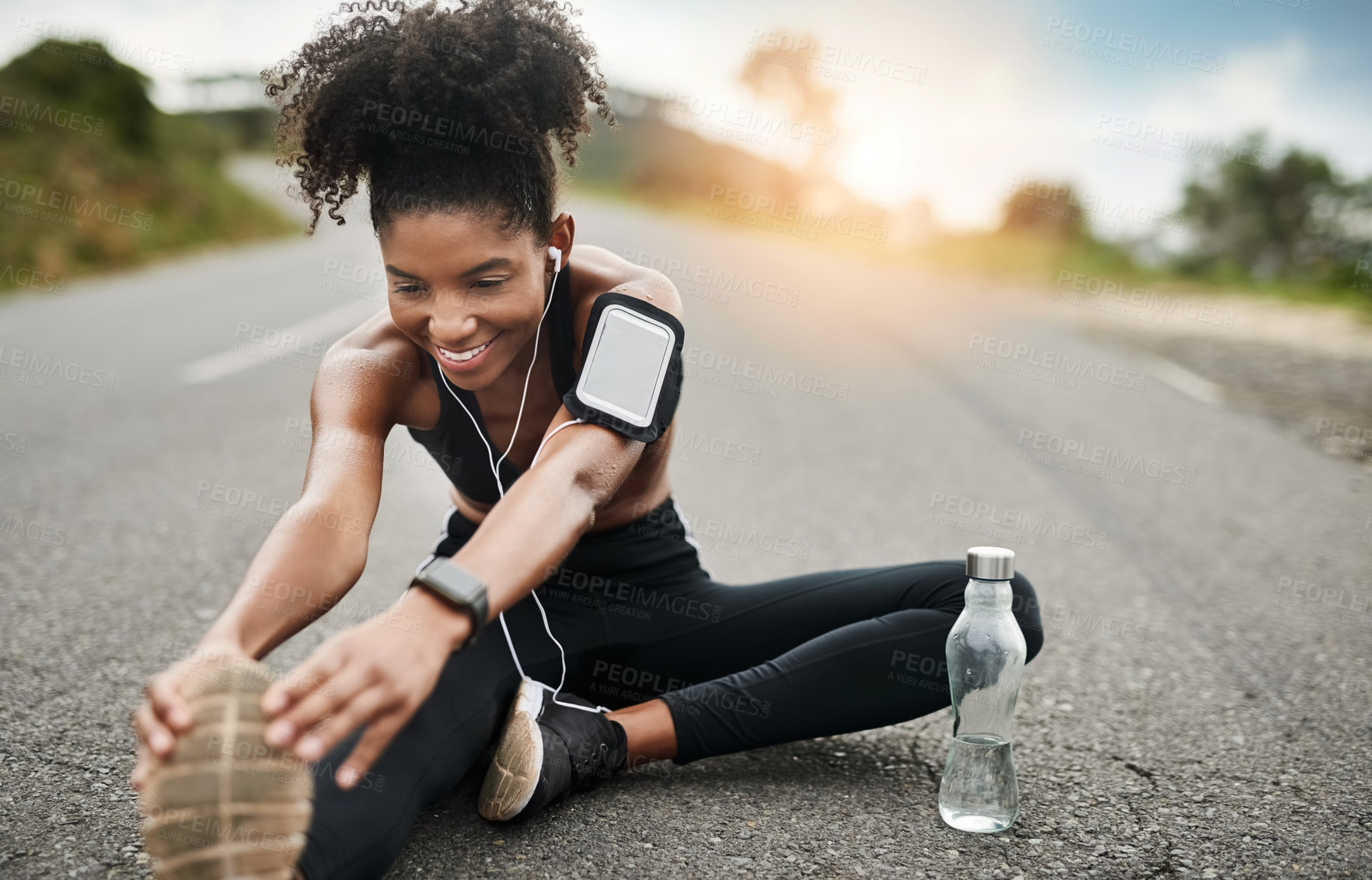 Buy stock photo Fitness, stretching and black woman on road with earphones for wellness, health and sports in city. Runner, happy and person listen to audio, music or podcast for exercise, training and workout 
