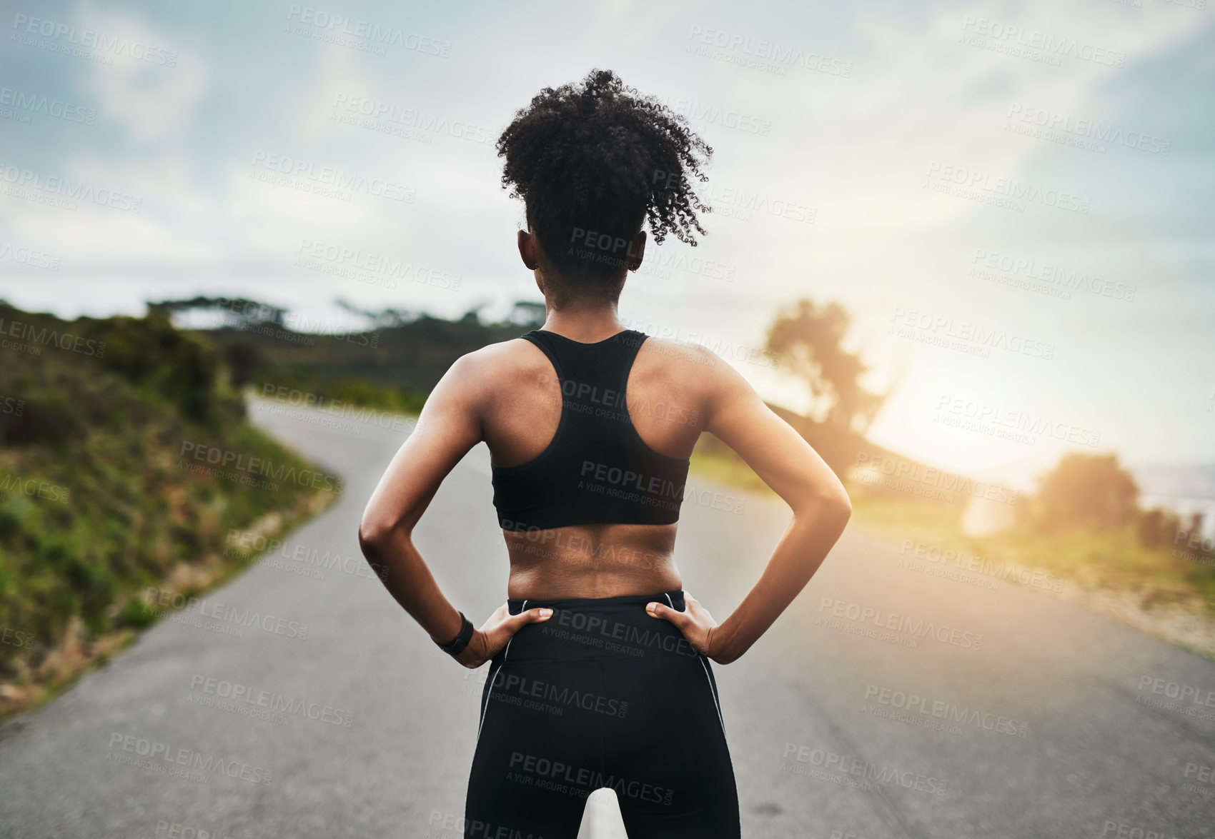 Buy stock photo Rearview shot of an unrecognizable young sportswoman standing with her hands on her hips outside