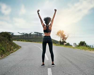 Buy stock photo Rearview shot of an unrecognizable young sportswoman cheering in celebration outside