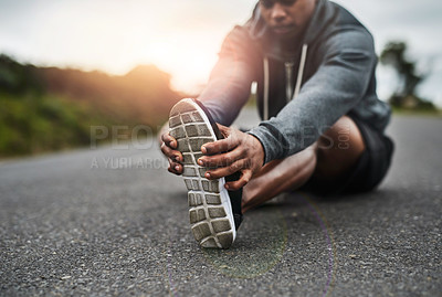 Buy stock photo Cropped shot of a handsome young sportsman warming up for a workout outdoors