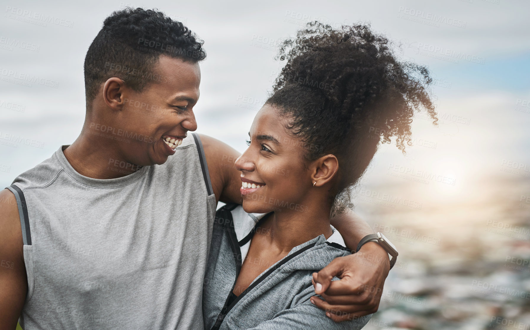 Buy stock photo Cropped shot of an affectionate and athletic young couple standing with their arms around one another outdoors