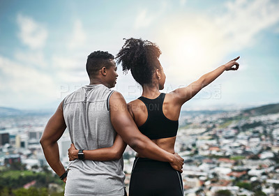 Buy stock photo Rearview shot of a young sportswoman showing her athletic boyfriend something while standing with their arms around one another outdoors