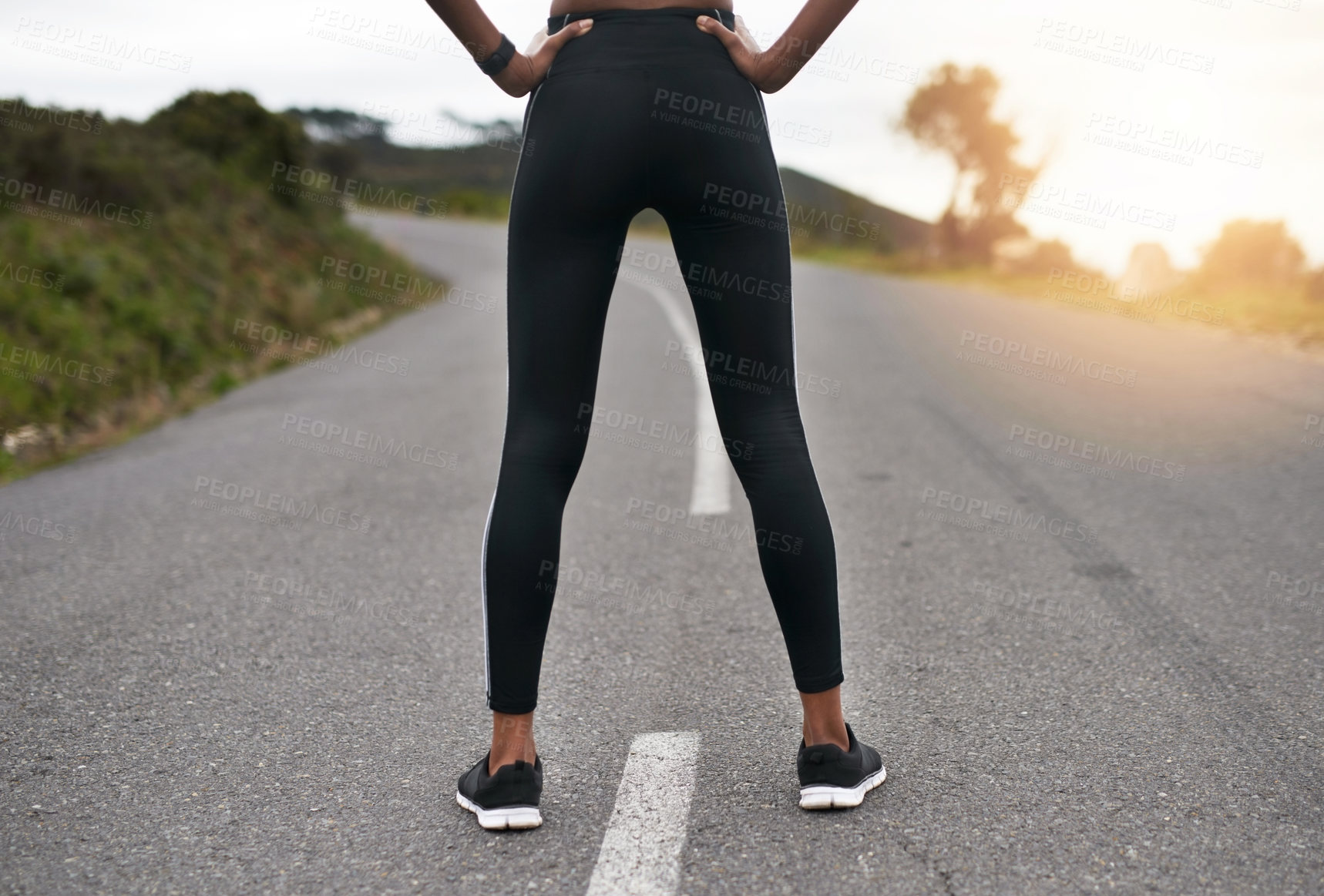 Buy stock photo Rearview shot of an unrecognizable young sportswoman standing with her hands on her hips outside