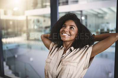 Buy stock photo Shot of a happy young businesswoman relaxing at her desk in a modern office