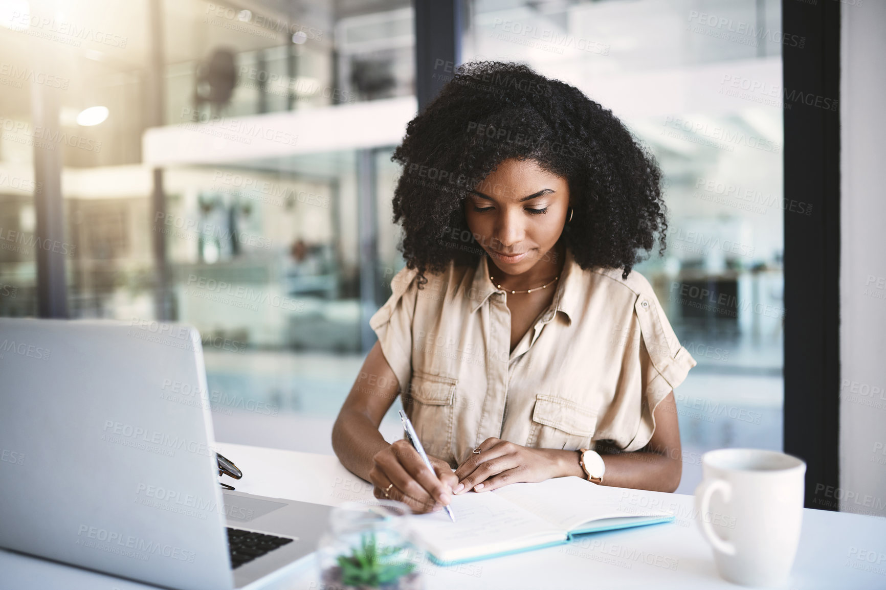 Buy stock photo Shot of a young businesswoman writing notes at her desk in a modern office