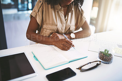 Buy stock photo Shot of a young businesswoman writing notes at her desk in a modern office