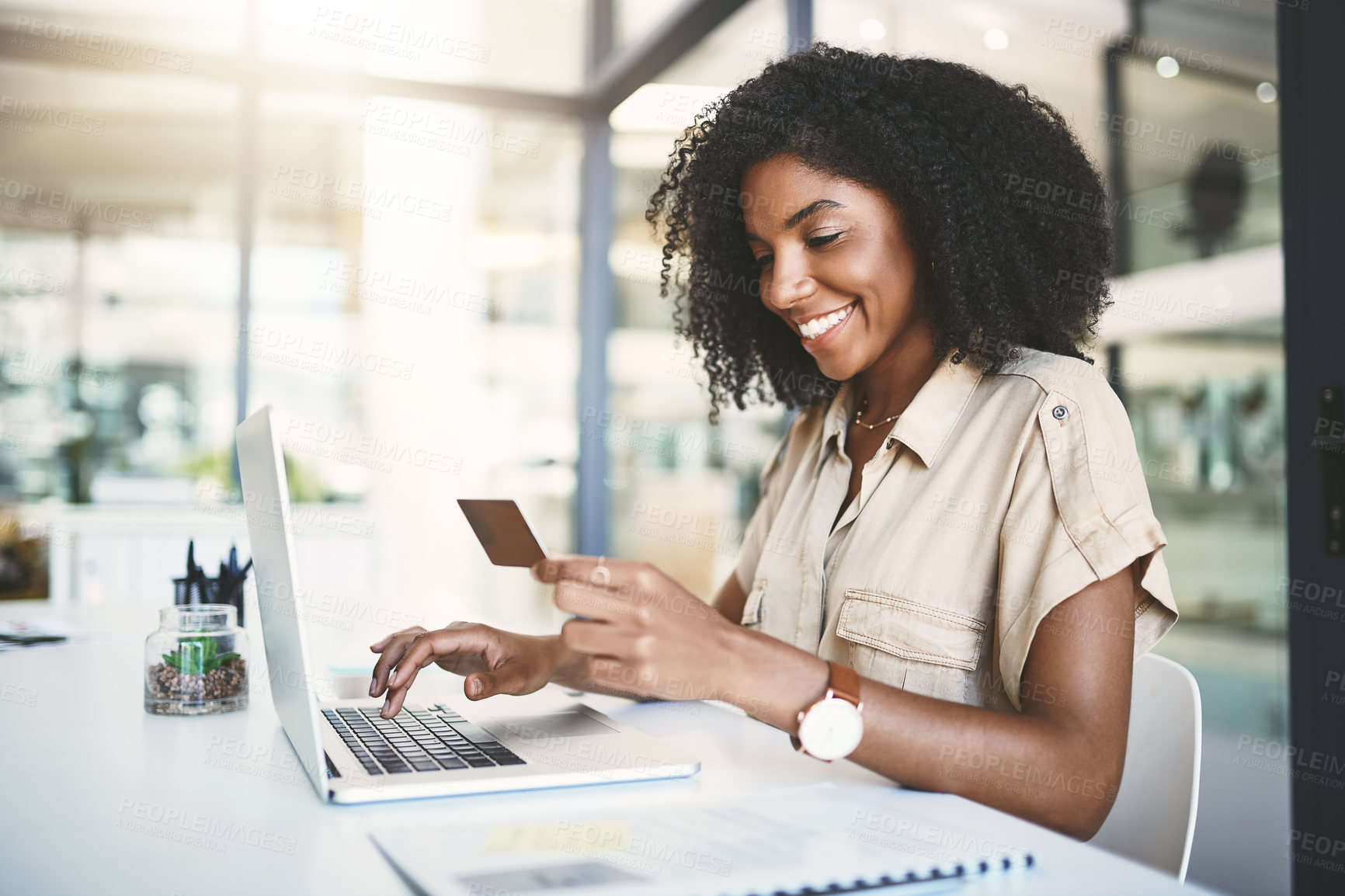 Buy stock photo Shot of a young businesswoman using a credit card and laptop in a modern office