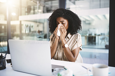 Buy stock photo Shot of a young businesswoman blowing her nose with a tissue while working in a modern office