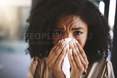 Buy stock photo Portrait of a young businesswoman blowing her nose with a tissue while working in a modern office