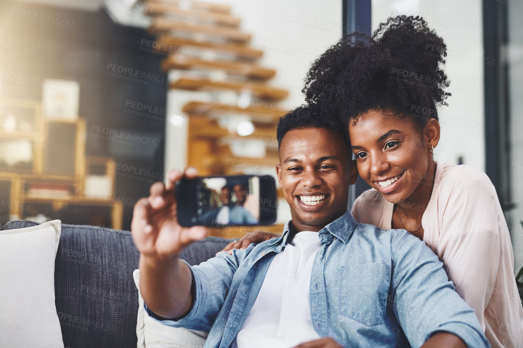 Buy stock photo Shot of a happy young couple taking selfies together on the sofa at home