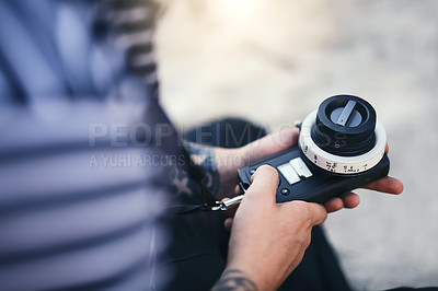 Buy stock photo Closeup of an unrecognizable man making a few adjustments on a state of the art video camera on a beach during the day