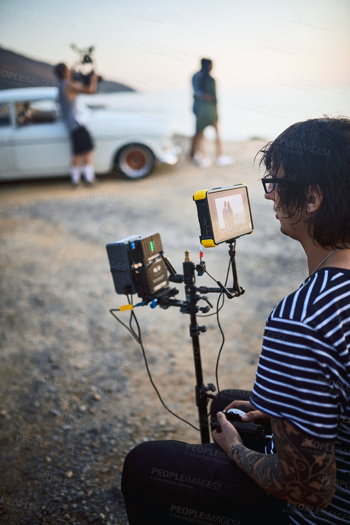 Buy stock photo Photographer, man and camera on set at beach for filmmaking, coastline cinema or videography in nature. Portable technology, cameraman or person with recording equipment by ocean for content creation