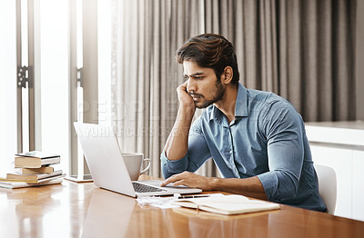 Buy stock photo Cropped shot of a handsome young businessman working on his laptop in the office at home