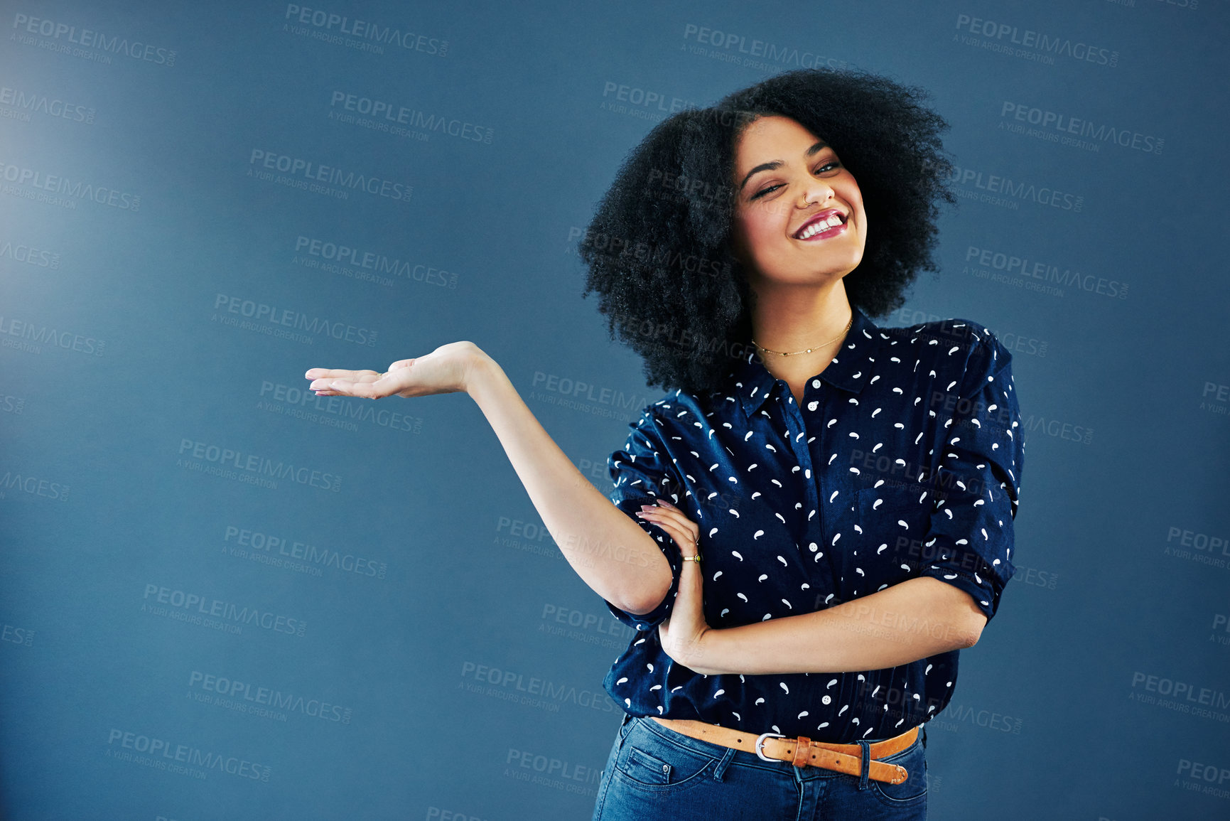 Buy stock photo Studio shot of a young woman gesturing towards copy space against a blue background