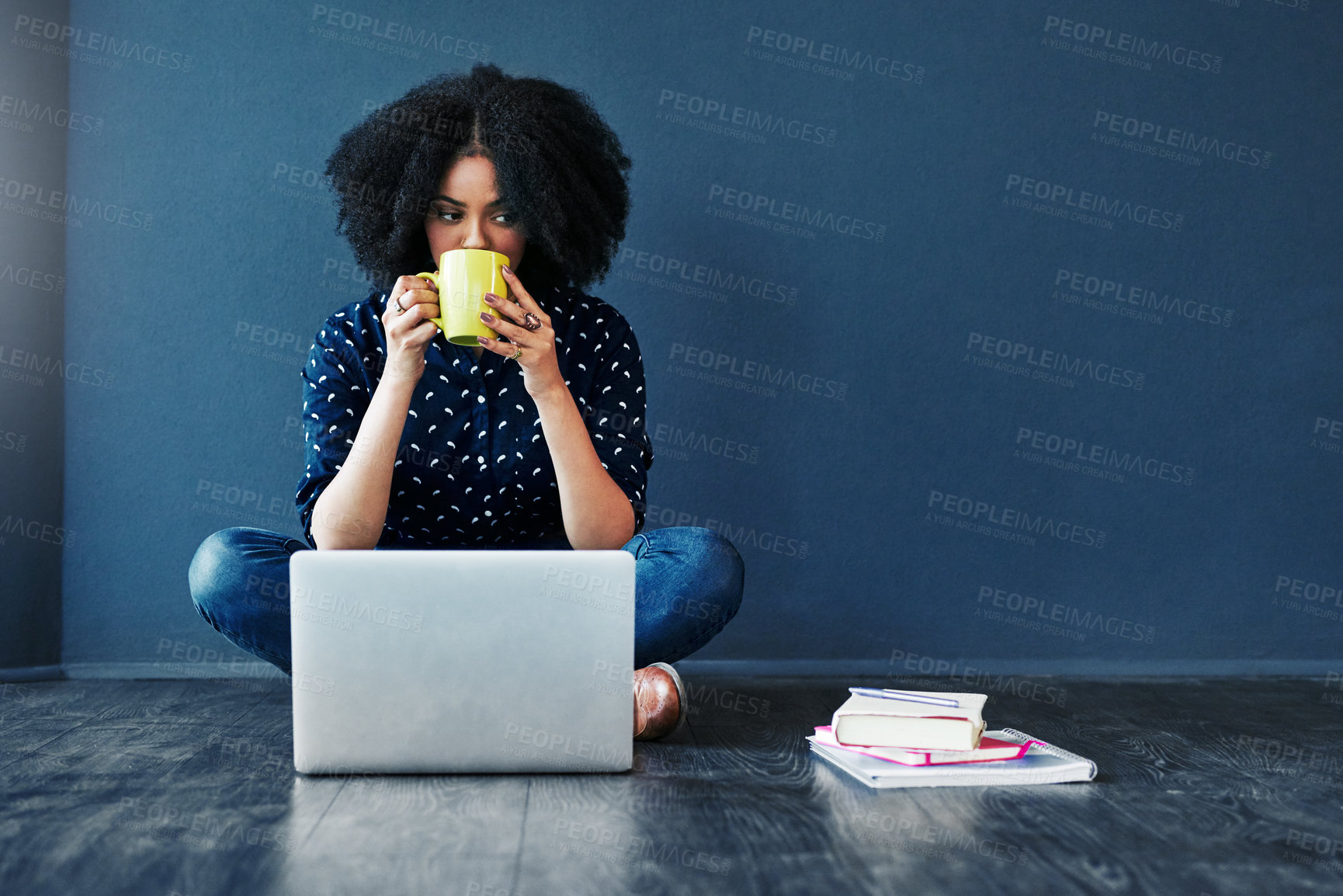 Buy stock photo Studio shot of an attractive young woman having coffee while using a laptop against a blue background