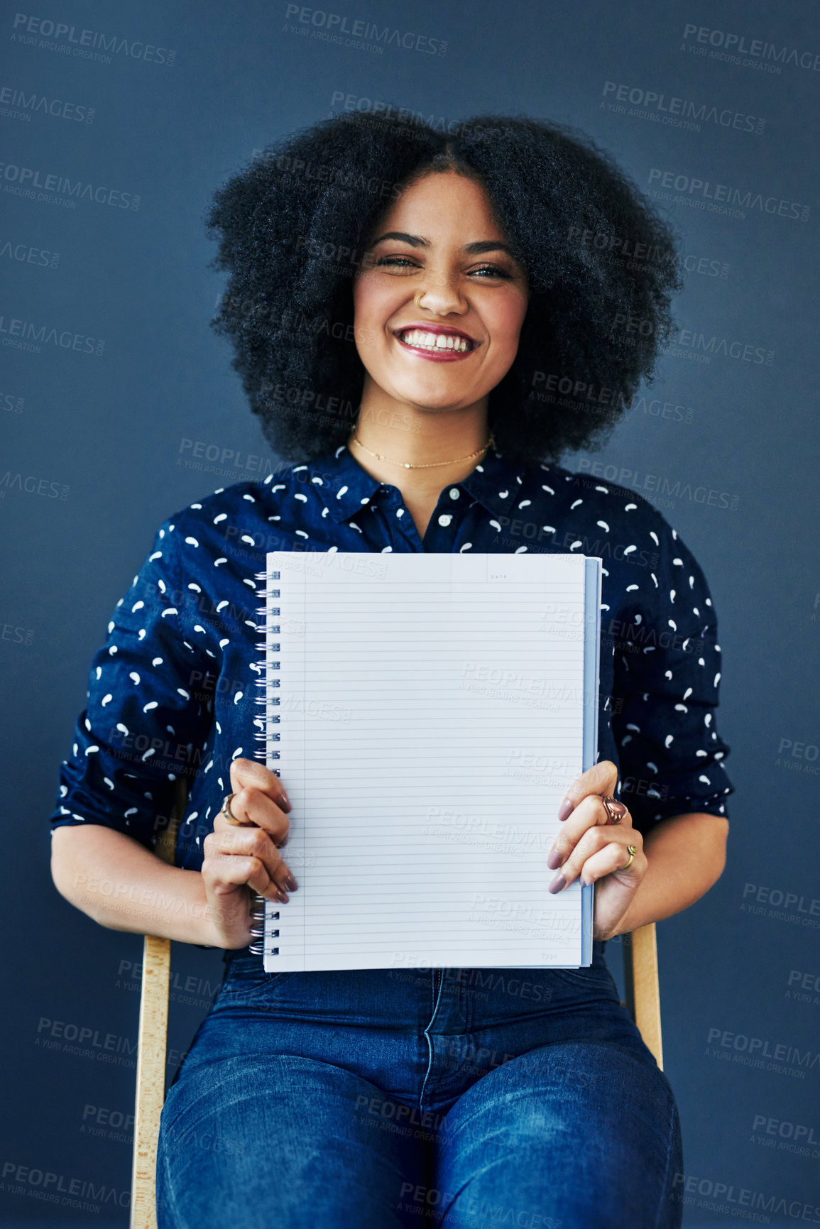 Buy stock photo Studio shot of a young woman holding up a blank notebook against a blue background