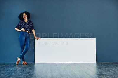 Buy stock photo Studio shot of a young woman leaning against a blank placard against a blue background