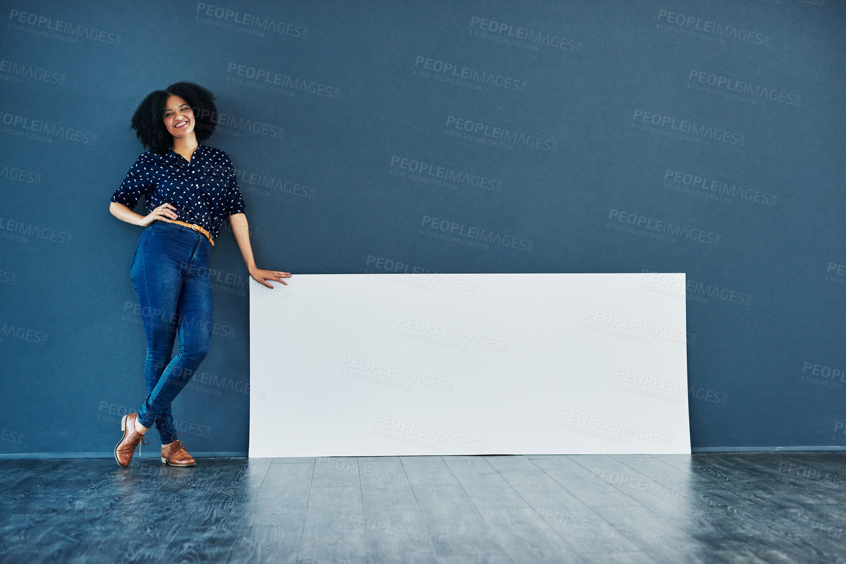 Buy stock photo Studio shot of a young woman leaning against a blank placard against a blue background