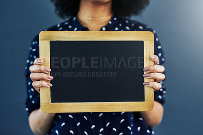 Buy stock photo Cropped studio shot of a woman holding a blank chalkboard against a blue background