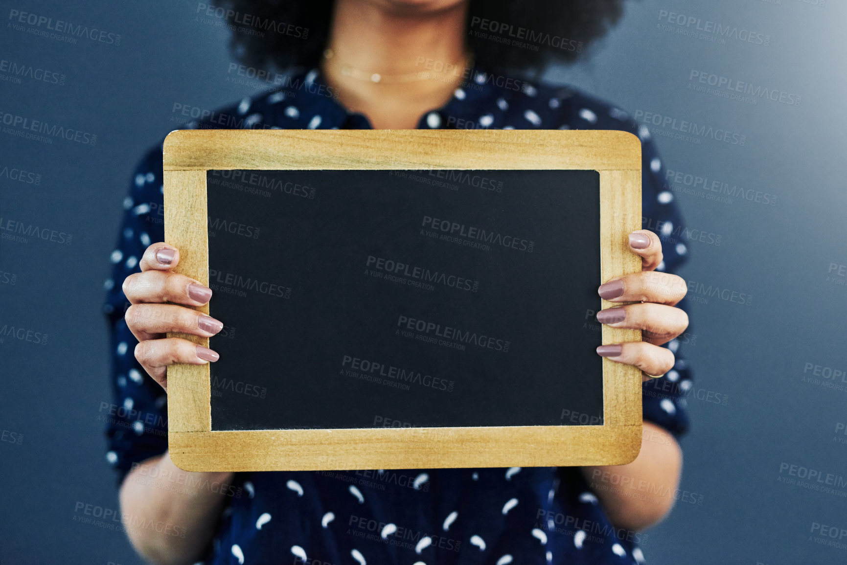 Buy stock photo Cropped studio shot of a woman holding a blank chalkboard against a blue background