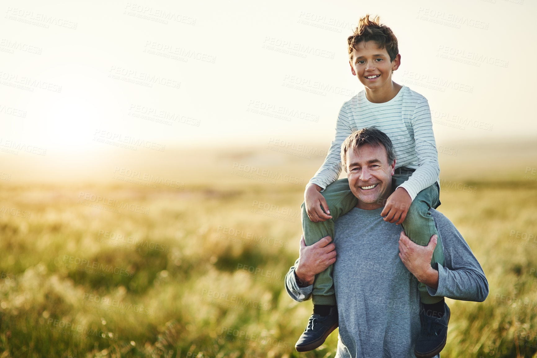 Buy stock photo Portrait, father and carrying of son in nature, love and smile for family in space, sunshine and grass. Countryside, dad and visit of Texas with boy for fresh air, man and bonding with child in farm