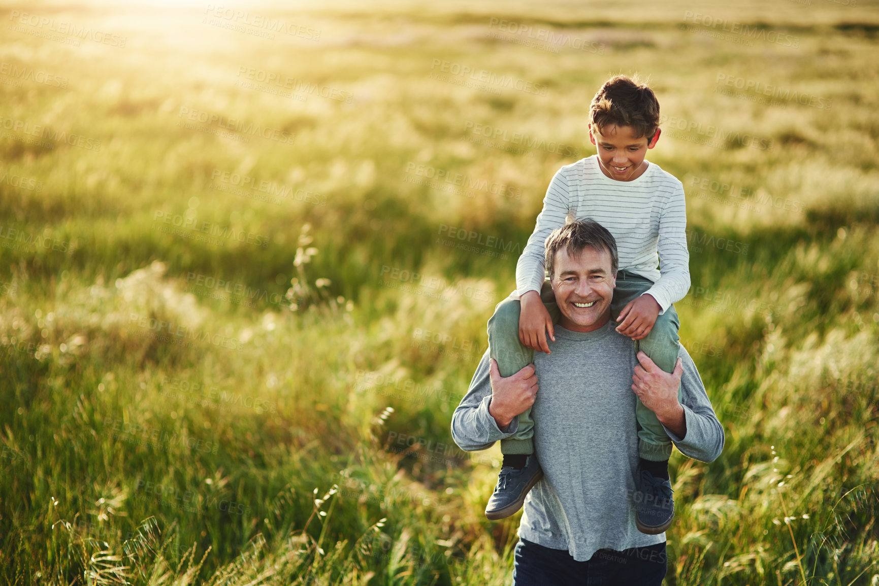 Buy stock photo Shot of a father carrying his son on his shoulders outdoors