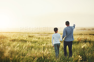 Buy stock photo Rearview shot of a father and his son walking on a field