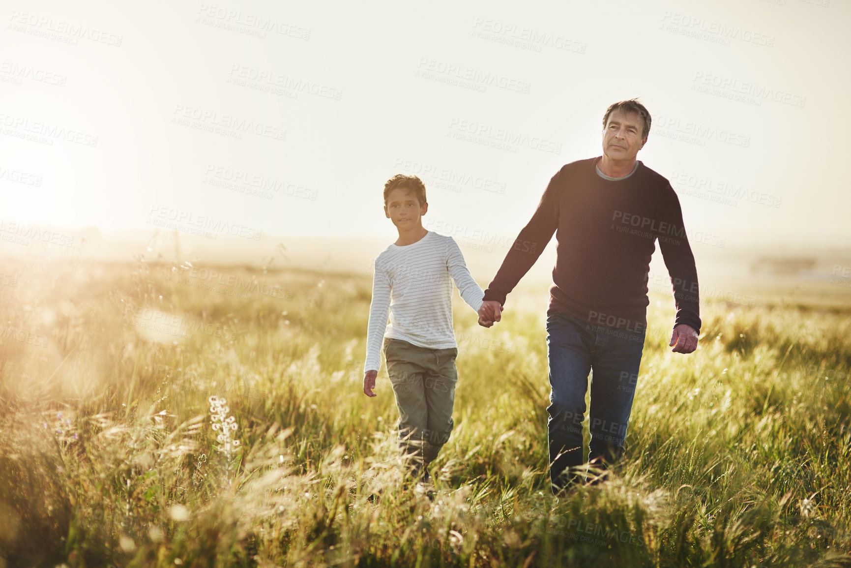 Buy stock photo Holding hands, walking and dad with child in nature at sunset for bonding together on vacation. Happy, farm and father with boy kid on adventure, holiday or weekend trip in agriculture countryside.