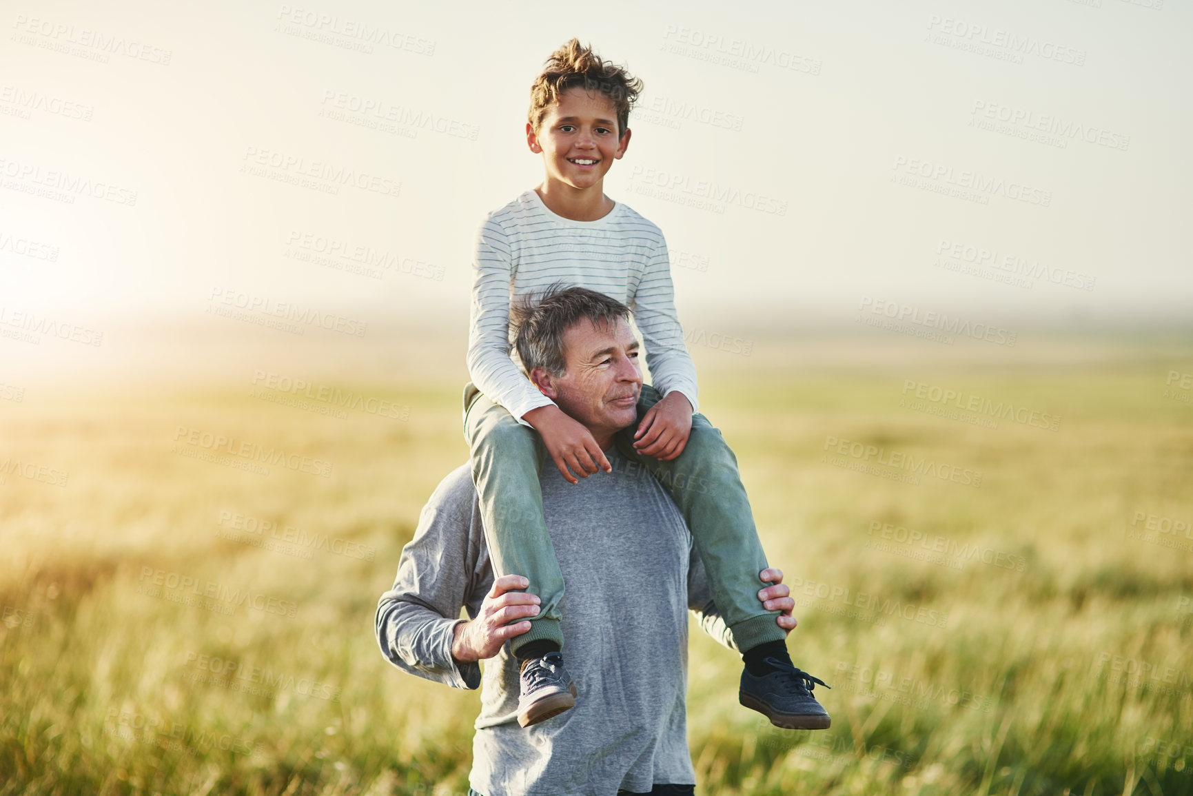 Buy stock photo Piggyback, father and portrait of son in nature, love and smile for family in space, sunshine and grass. Countryside, dad and visit of Texas with boy for fresh air, man and bonding with child in farm