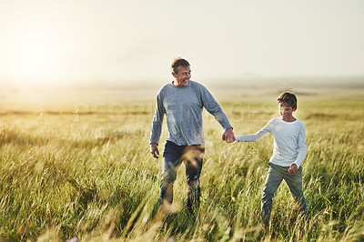 Buy stock photo Shot of a father and his son walking on a field